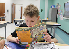 Student reading a book at his desk